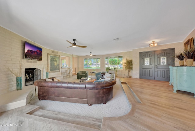 living room featuring a brick fireplace, ceiling fan, and light hardwood / wood-style flooring