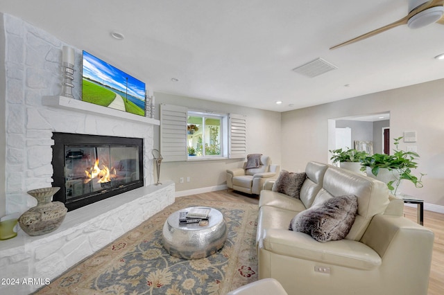 living room with light hardwood / wood-style floors and a stone fireplace