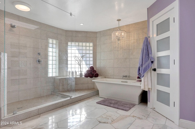 bathroom with tile patterned floors, separate shower and tub, tile walls, and a notable chandelier