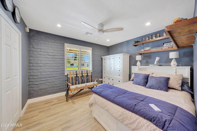 bedroom with ceiling fan, brick wall, and light wood-type flooring