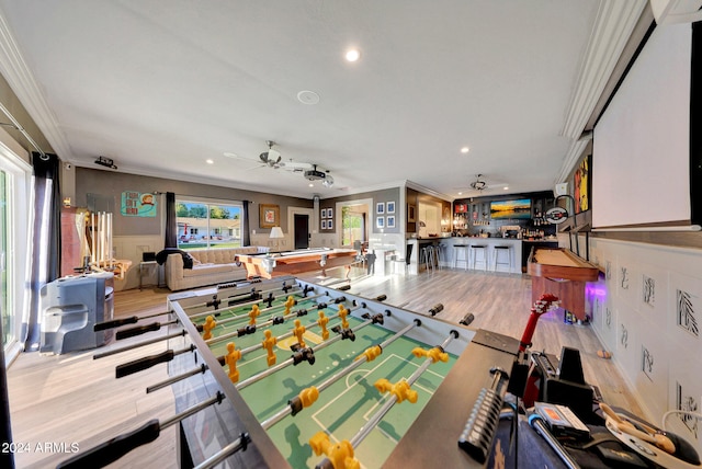 rec room with ceiling fan, light hardwood / wood-style flooring, and ornamental molding