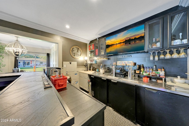 bar with light hardwood / wood-style floors, a notable chandelier, ornamental molding, stainless steel counters, and pendant lighting