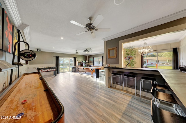 recreation room featuring hardwood / wood-style floors, a healthy amount of sunlight, and crown molding