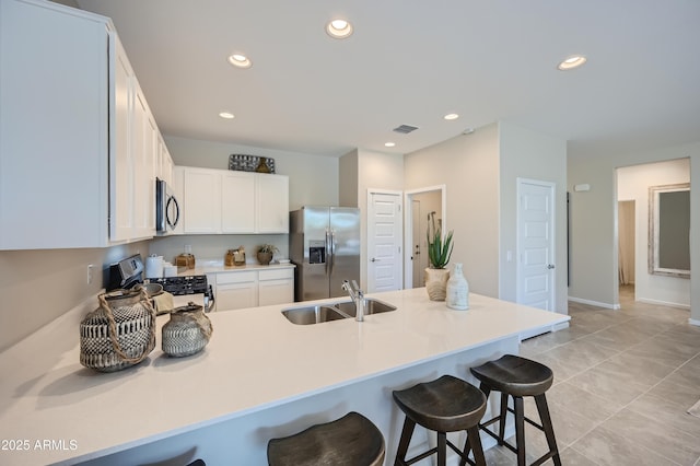 kitchen featuring a breakfast bar, sink, white cabinetry, kitchen peninsula, and stainless steel appliances