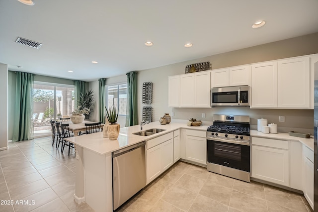 kitchen featuring sink, white cabinetry, light tile patterned floors, kitchen peninsula, and stainless steel appliances