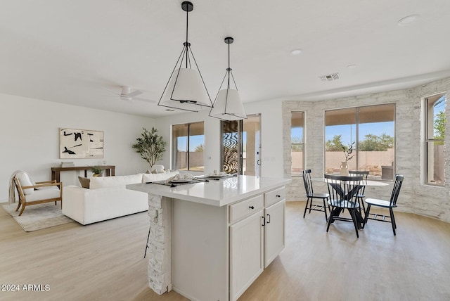 kitchen with decorative light fixtures, white cabinetry, plenty of natural light, and light hardwood / wood-style flooring