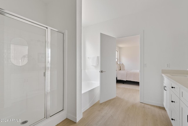 bathroom with independent shower and bath, vanity, and wood-type flooring