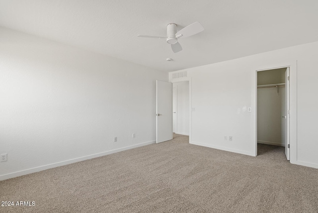 unfurnished bedroom featuring ceiling fan, a walk in closet, carpet floors, and a closet