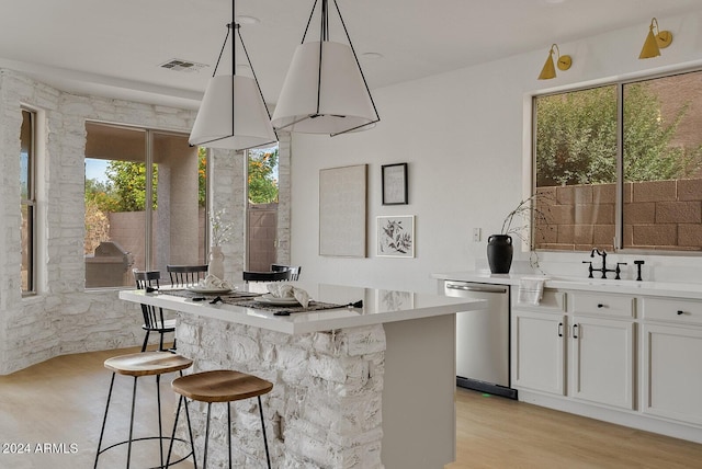 interior space featuring pendant lighting, dishwasher, white cabinets, light hardwood / wood-style flooring, and a healthy amount of sunlight