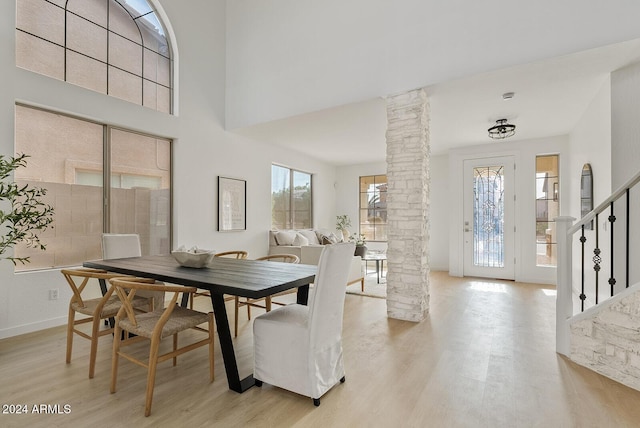 dining room featuring ornate columns, light hardwood / wood-style floors, and a high ceiling