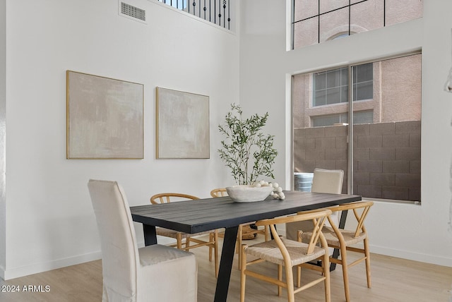 dining space with a towering ceiling and light wood-type flooring