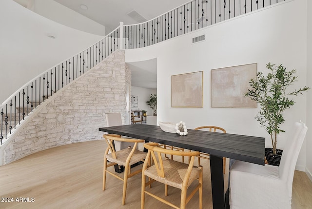 dining space featuring light hardwood / wood-style floors and a high ceiling