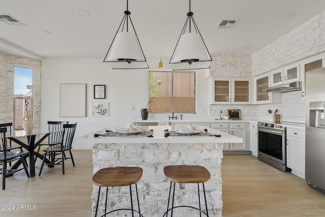 kitchen with a kitchen bar, light hardwood / wood-style flooring, white cabinets, and appliances with stainless steel finishes