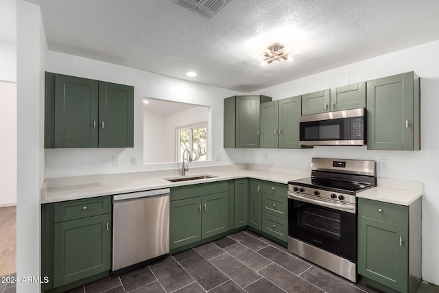 kitchen featuring sink, green cabinetry, stainless steel appliances, and a textured ceiling