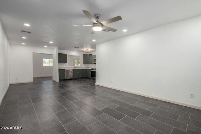 unfurnished living room featuring ceiling fan and dark tile patterned floors