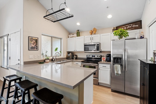 kitchen featuring appliances with stainless steel finishes, a breakfast bar, sink, and white cabinets