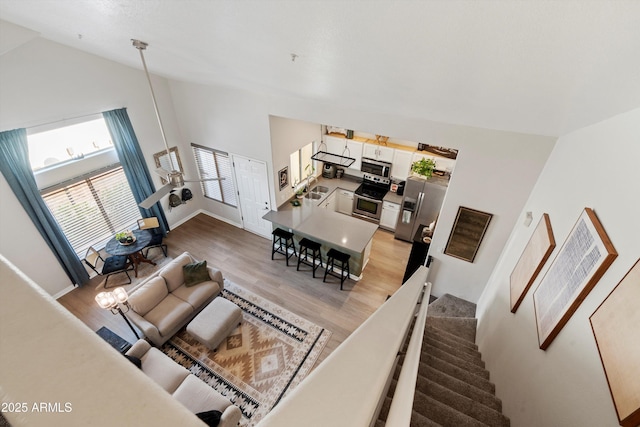 living room with high vaulted ceiling, sink, and light hardwood / wood-style floors