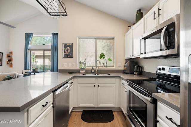 kitchen with white cabinetry, stainless steel appliances, kitchen peninsula, and sink