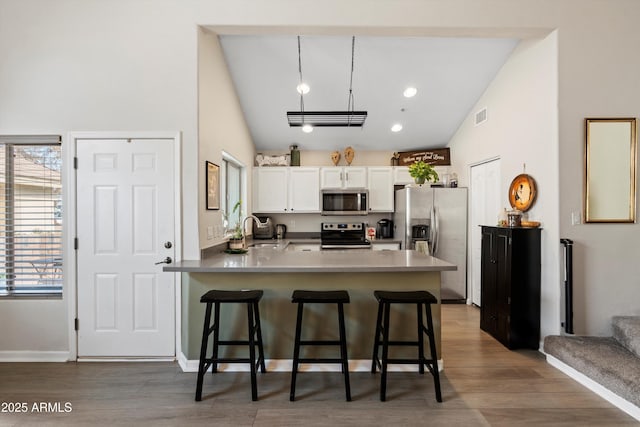 kitchen featuring stainless steel appliances, white cabinetry, a breakfast bar, and kitchen peninsula