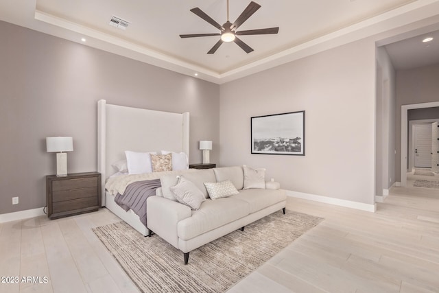 bedroom featuring light hardwood / wood-style flooring, ceiling fan, and a raised ceiling