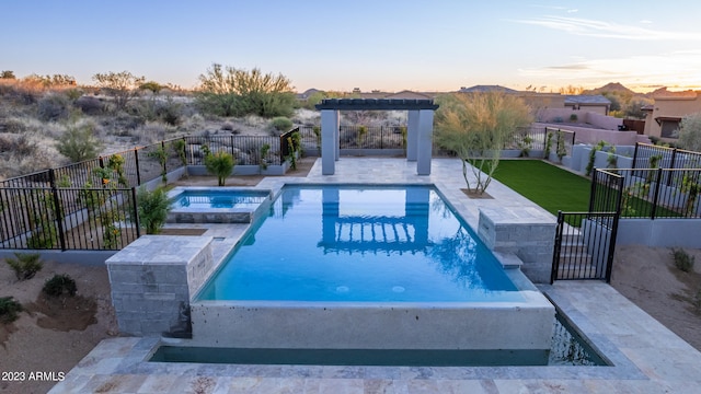 pool at dusk featuring a mountain view, an in ground hot tub, and a patio area