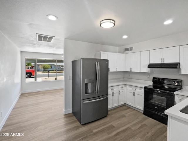 5308 N 77th Dr, Glendale, AZ 85303 - kitchen with under cabinet range hood, visible vents, stainless steel fridge, black range with electric cooktop, and white cabinetry