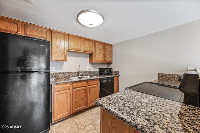 kitchen with sink, light tile patterned floors, dark stone counters, and black appliances