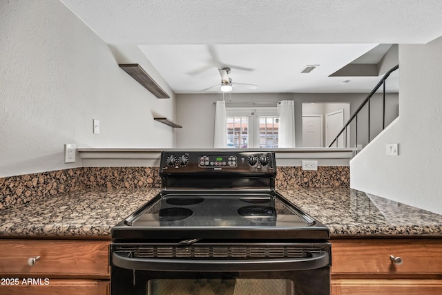 kitchen featuring ceiling fan, black range with electric cooktop, and dark stone countertops