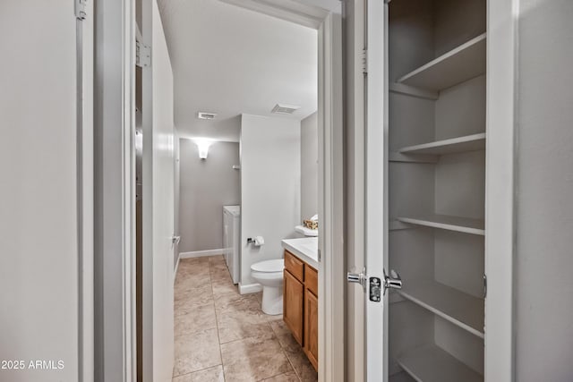 bathroom featuring vanity, washer / clothes dryer, and toilet