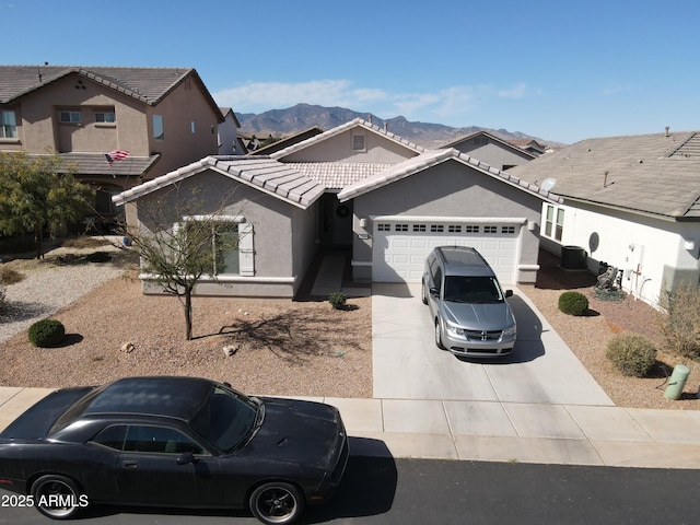 view of front of house featuring concrete driveway, a tile roof, an attached garage, cooling unit, and stucco siding