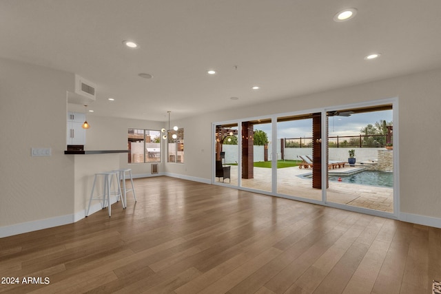 unfurnished living room featuring wood-type flooring and a notable chandelier