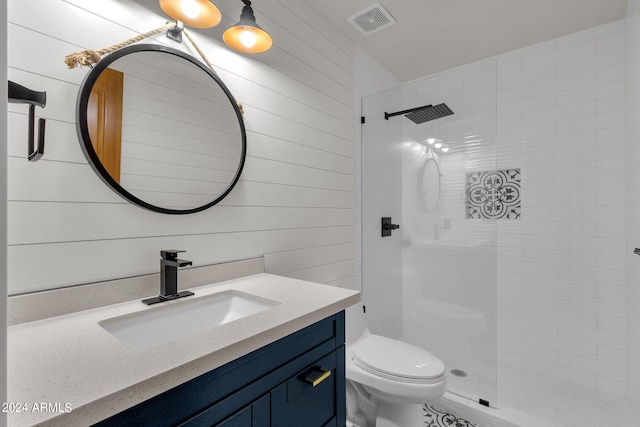 bathroom featuring wooden walls, tiled shower, vanity, and toilet