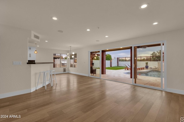 unfurnished living room featuring plenty of natural light, an inviting chandelier, and hardwood / wood-style flooring