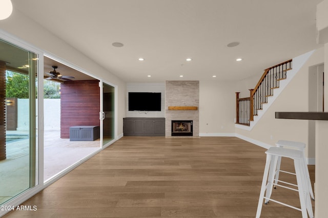 unfurnished living room with wood-type flooring, ceiling fan, and a fireplace