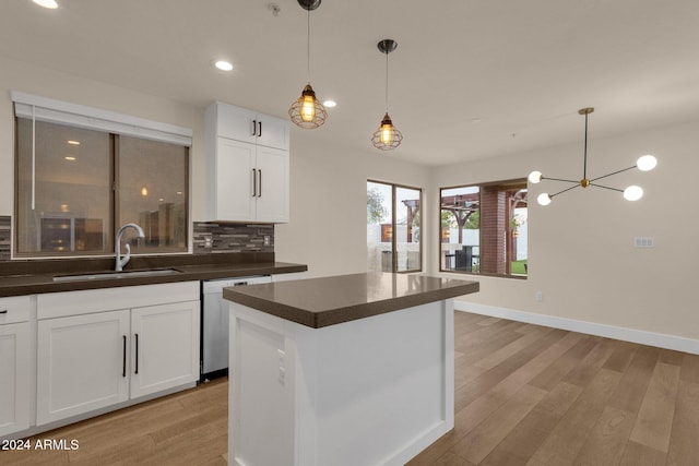 kitchen featuring dishwasher, light hardwood / wood-style floors, sink, white cabinets, and decorative backsplash