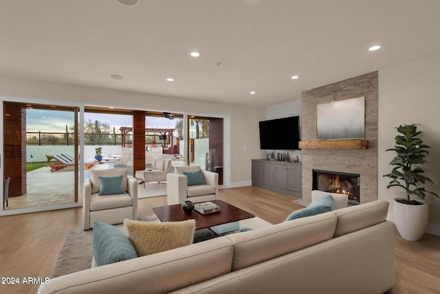 living room featuring a stone fireplace and light hardwood / wood-style flooring