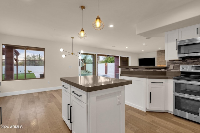 kitchen featuring appliances with stainless steel finishes, hanging light fixtures, and white cabinets