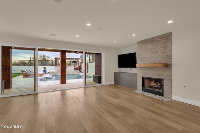 unfurnished living room featuring light wood-type flooring, a fireplace, and a wealth of natural light