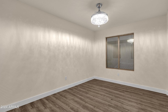 spare room featuring a notable chandelier and dark hardwood / wood-style floors