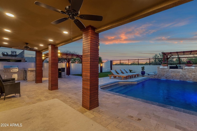 pool at dusk with area for grilling, ceiling fan, a patio area, and grilling area