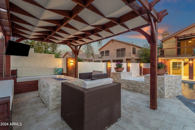 patio terrace at dusk with a pergola, an outdoor living space with a fire pit, and a balcony