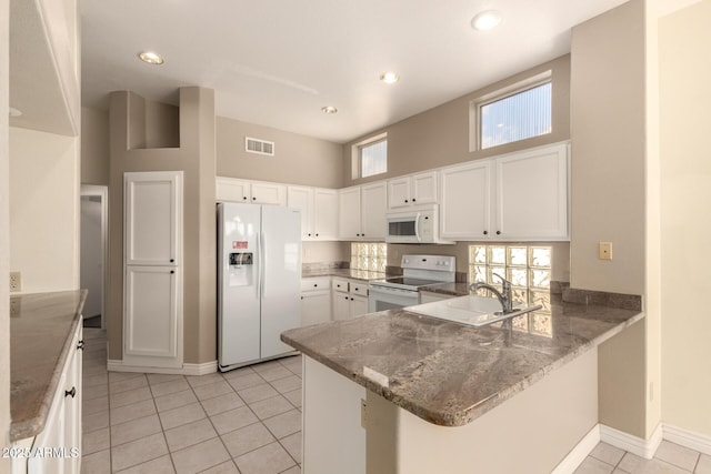 kitchen with white appliances, light tile patterned floors, visible vents, a peninsula, and white cabinetry