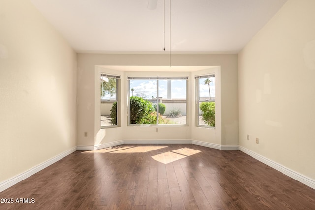 spare room with baseboards and wood finished floors