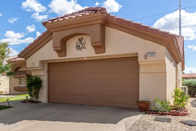 view of front of property with stucco siding, a garage, driveway, and a tiled roof