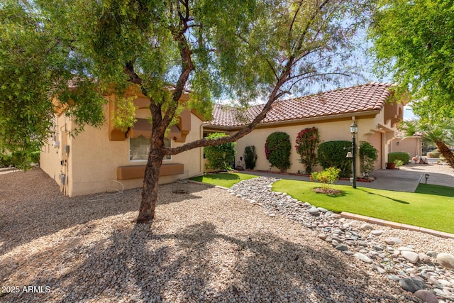 view of front of property featuring stucco siding, a tiled roof, and a front lawn