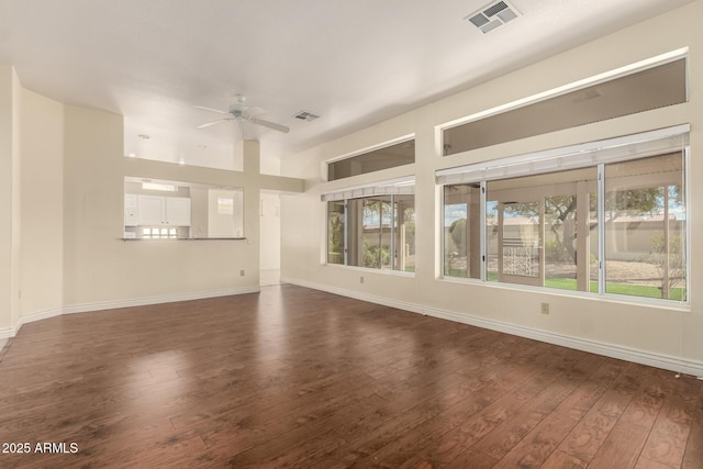 unfurnished living room featuring visible vents, baseboards, dark wood-style flooring, and a ceiling fan