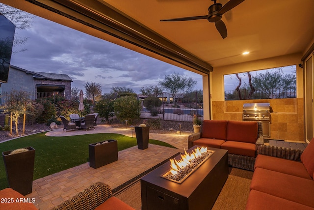 patio terrace at dusk featuring an outdoor kitchen, area for grilling, and an outdoor living space with a fire pit