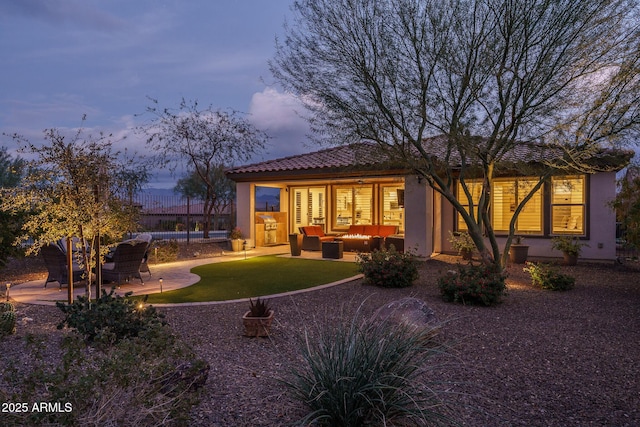 back house at dusk featuring an outdoor hangout area and a patio area