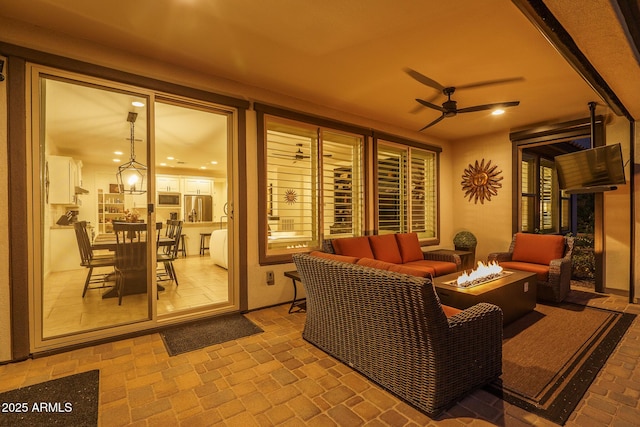 view of patio / terrace featuring ceiling fan and an outdoor living space with a fire pit