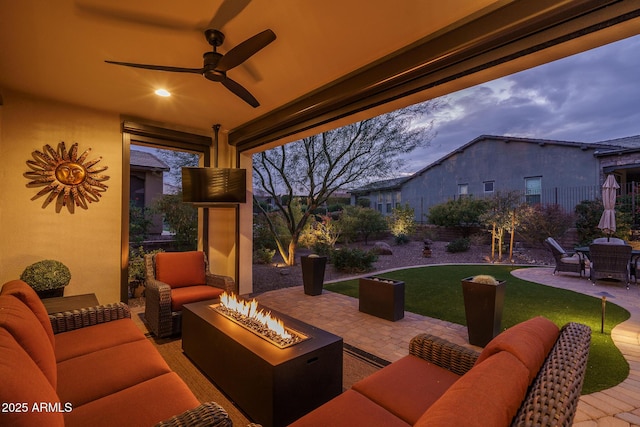 view of patio / terrace with ceiling fan and an outdoor living space with a fire pit